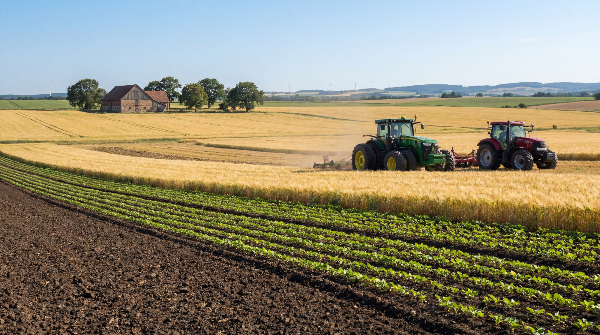 Deux tracteurs travaillent dans un champ de blé doré près d'une exploitation agricole sous un ciel bleu dégagé.